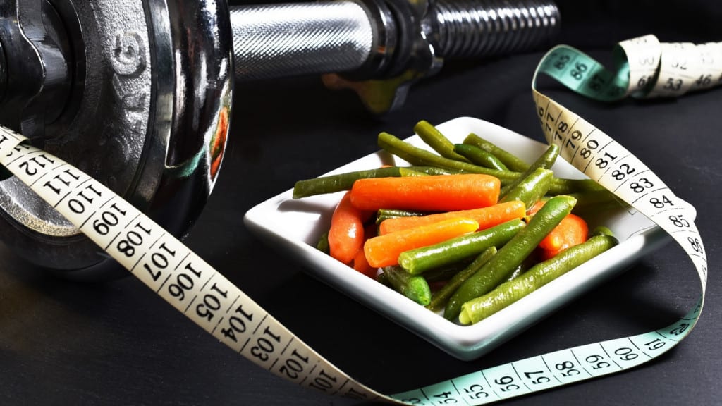 dumbbell, bowl of carrot and green beans, and a tape measure
